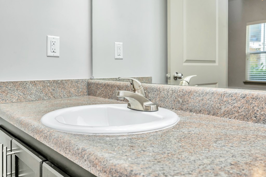 A bathroom sink with a granite countertop and a silver faucet.